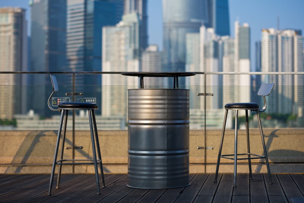 Two stools and a table on a balcony with a view of a city